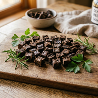 Dehydrated beef heart dog treat pieces on a wooden cutting board with decorative herbs